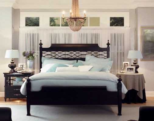 A bedroom with a black bed and a blue comforter, choosing and styling a bedside table.