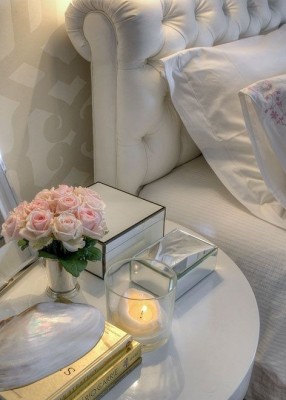 A white bedside table with flowers and a candle for styling purposes.