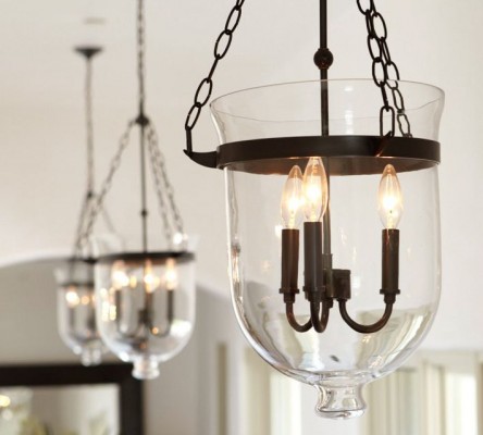 Three glass pendant lights hanging over a dining room table in a traditional kitchen.