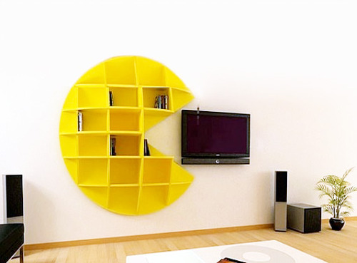 A living room with floating shelves and a yellow pac man bookcase.