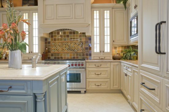 A traditional kitchen with white cabinets and a blue island.