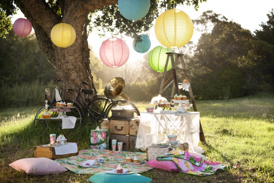A backyard dining setup with a picnic table adorned with colorful paper lanterns.