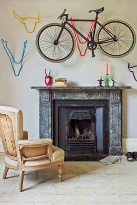 A bicycle hanging above a fireplace, serving as a unique storage solution in a living room.