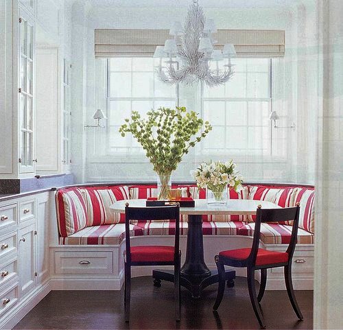 A white kitchen with red and white striped stools and a chandelier, perfect for designing a kitchen nook.