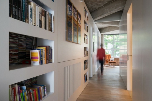 A person walking down a hallway with bookshelves in a loft space.