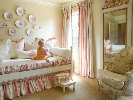 A girl sits in her pink and white bedroom.