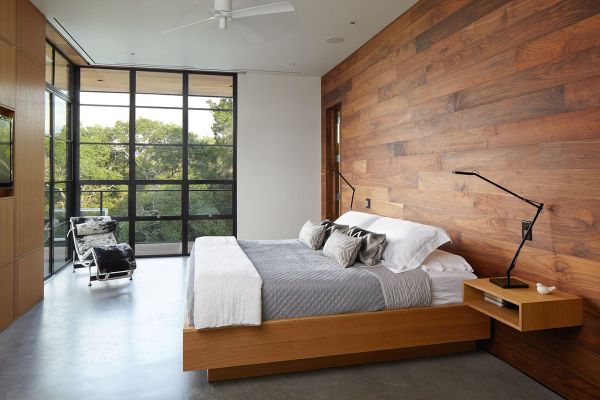 A modern bedroom featuring natural wood walls and a bed.