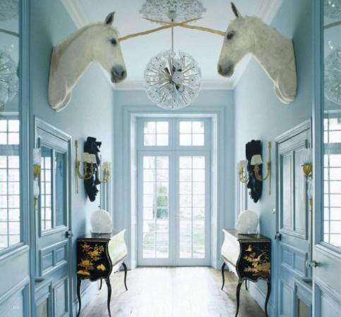 Whimsical hallway with horse heads and a chandelier.
