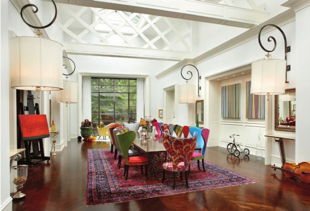 A dining room with whimsical colorful chairs and a chandelier.