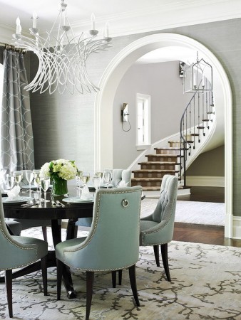 A formal dining room with blue chairs and a staircase featuring the basics of interior design.