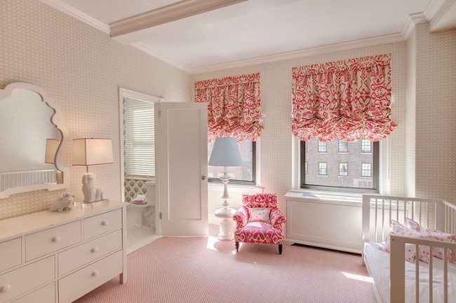 A pink and white baby room with a crib, dresser, and window treatments.
