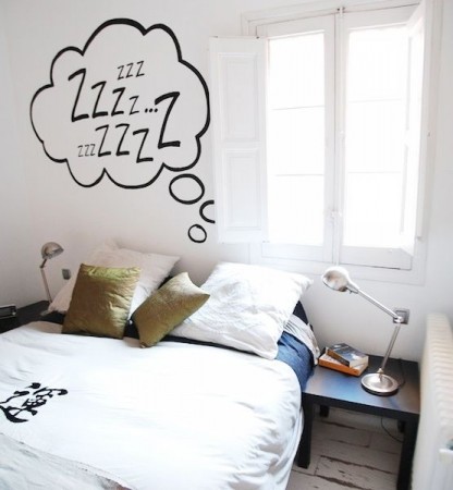 A whimsical bedroom with a bed and a wall decal with the word snooze.