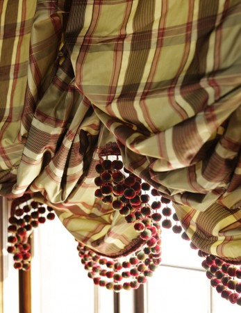 A plaid curtain hanging from a window providing window treatments.