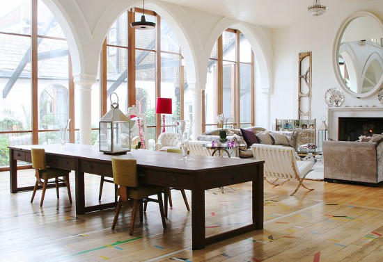 A dining room with a large table and chairs, converted from a church.