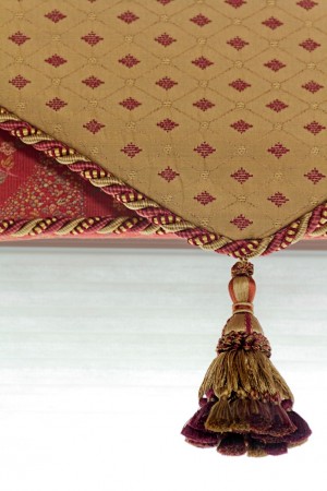 A red and gold tassel hanging from a window treatment.