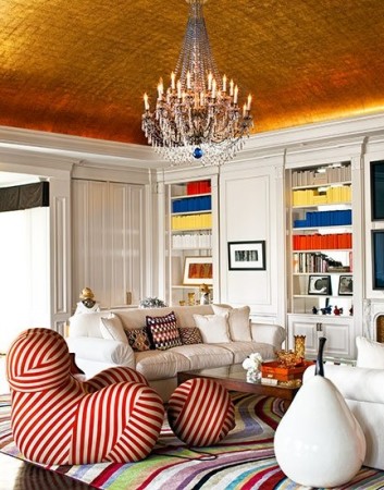 A living room with a whimsical ceiling and striped rug.