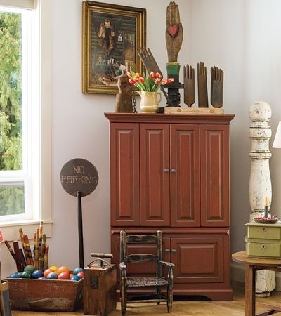 A living room with a whimsical red armoire and other items.