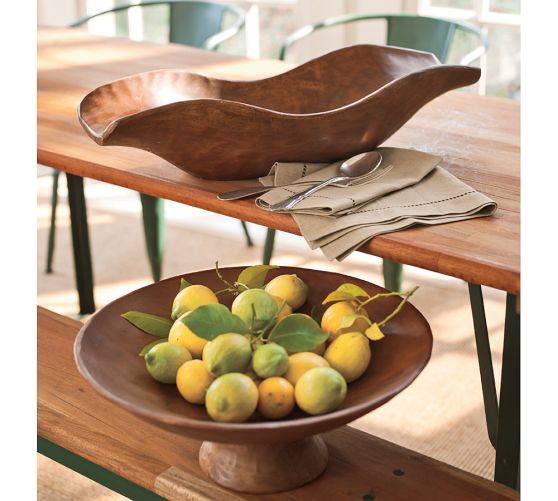 A bowl of lemons on a natural wood table.