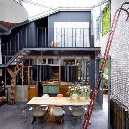 A loft space with a table, chairs, and a ladder.