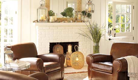 A living room with brown leather chairs and a fireplace decorated in the off-season.