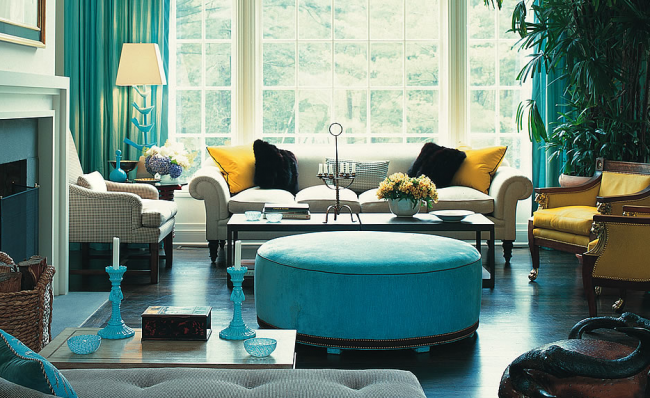 A living room showcasing the basics of interior design with blue curtains and a yellow ottoman.