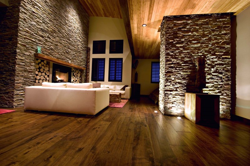 A living room with wood floors and a stone fireplace, showcasing natural wood elements in the home.