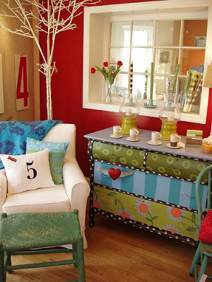 A whimsical room with a red wall and a colorful dresser.