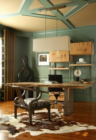 A masculine home office with green walls and a cowhide rug.