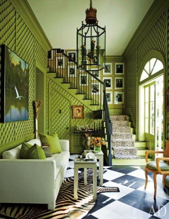 A living room with green walls and a zebra print rug featuring latticework furniture.