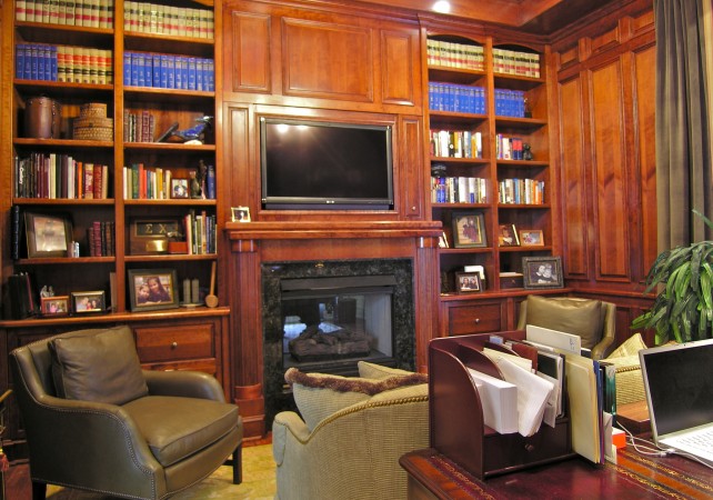 A masculine home office with bookshelves and a fireplace.