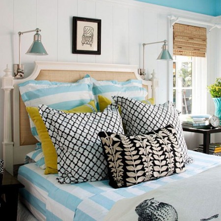A bedroom with blue walls and white bedding adorned with decorative pillows.