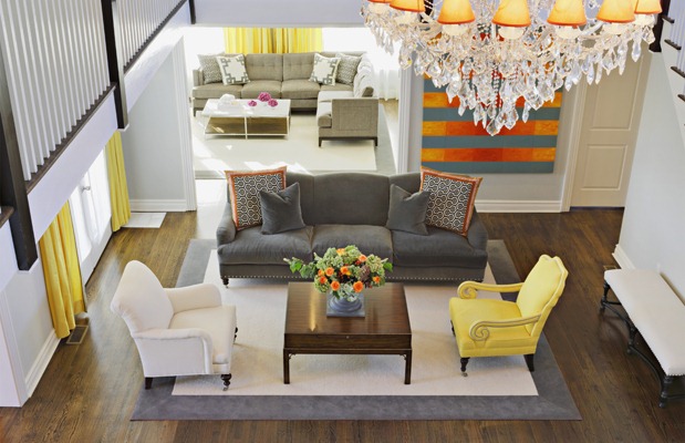 A staged living room with yellow furniture and a chandelier to attract potential buyers.