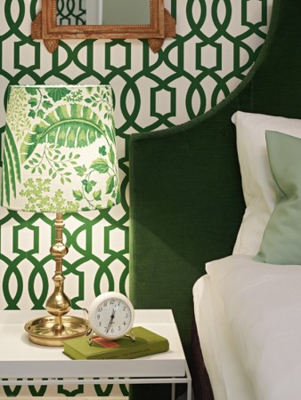 A green and white bedroom with a latticework mirror.