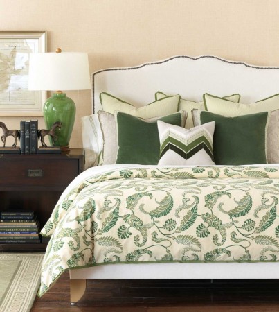 A green and white bedroom with a green and white comforter adorned with decorative pillows.