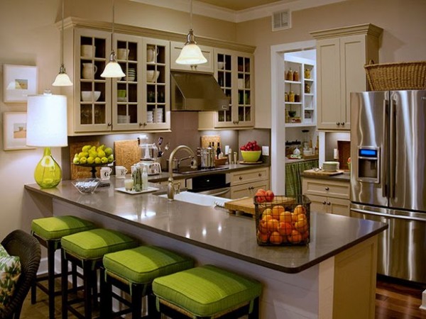 A kitchen staged with stainless steel appliances and green stools.