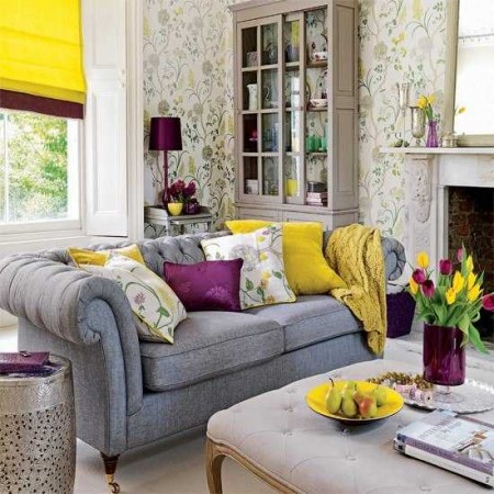 A yellow living room with floral wallpaper adorned with decorative pillows.