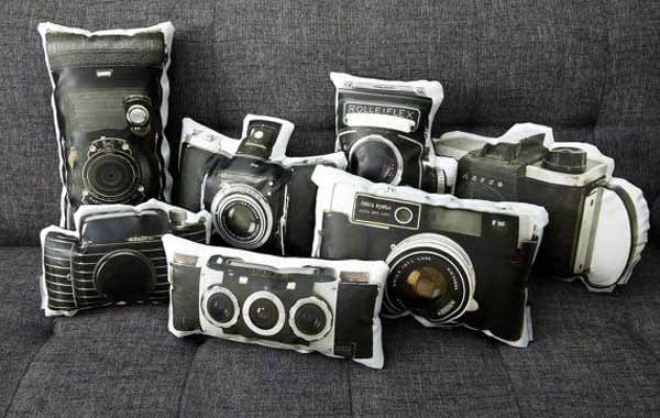 A collection of decorative vintage camera pillows on a couch.