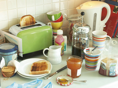 A kitchen counter staged with a toaster, plates, cups, and utensils.