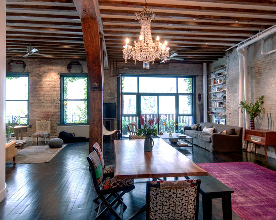 A warehouse converted into a home with a living room featuring a chandelier and wooden beams.