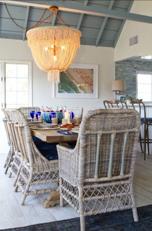 A coastal cottage dining room with wicker chairs and a chandelier.