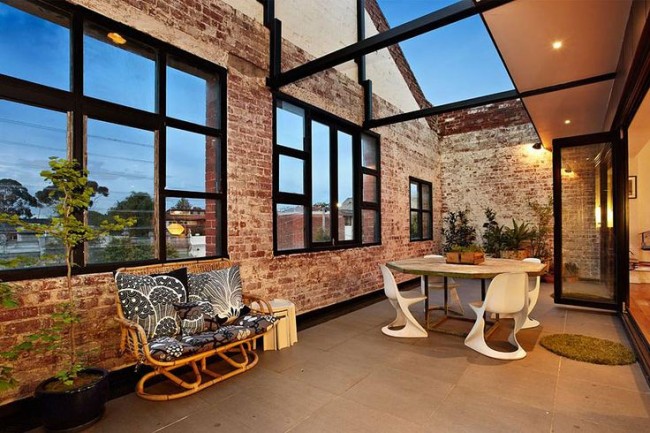 A brick patio transformed into a cozy outdoor dining area with a table and chairs for a warehouse to home conversion.