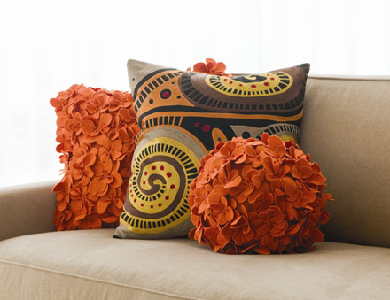 A beige couch with decorative orange pillows.