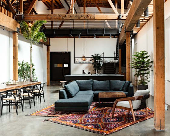 A warehouse to home conversion with a living room featuring wooden beams and a rug.