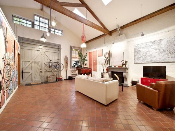 A spacious living room with a sizable painting on the wall in a warehouse to home conversion.