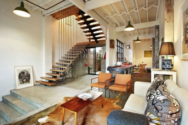 A warehouse to home conversion featuring a living room with stairs and a couch.