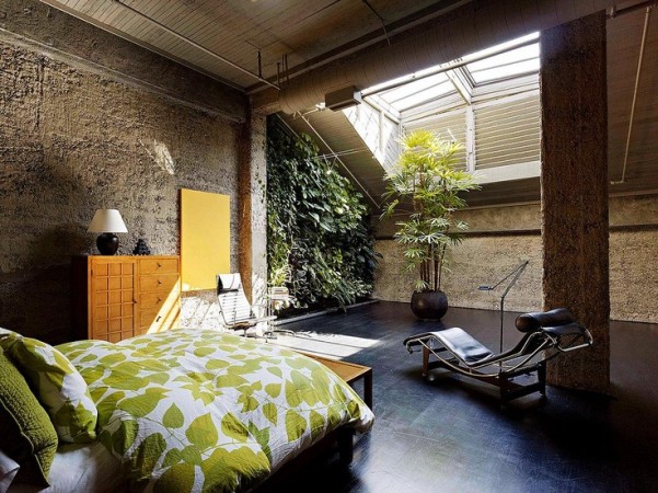 A bedroom in a warehouse to home conversion with a bed and a bedside table.