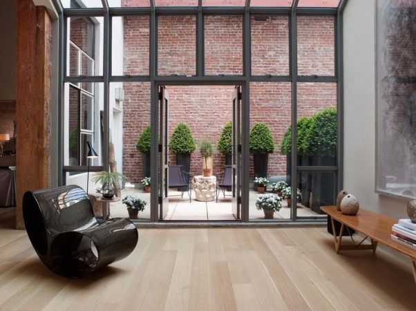 A warehouse converted into a home with large windows and a wooden floor.