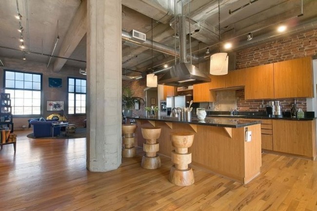 A spacious warehouse kitchen with wood floors and a bar stools, perfect for a home conversion project.