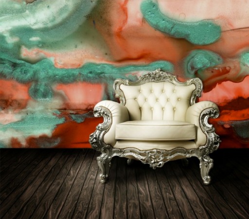 A chair in front of a vibrant wall with a watercolor design.