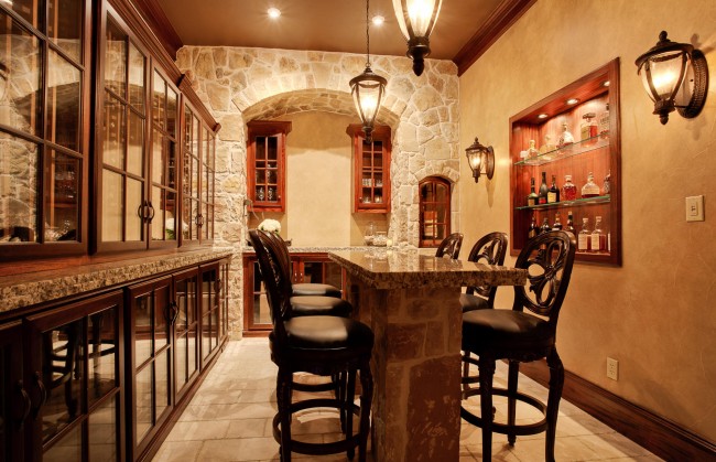 A home bar with a stone counter top and wine storage.